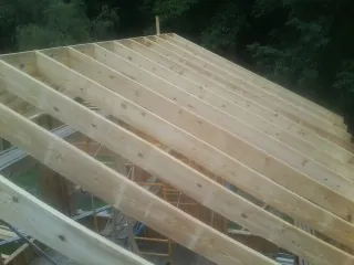 New roof rafters set over an addition before sheathing in West Henrietta