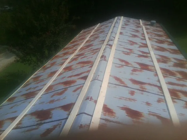 Rusted metal roof panels with new wood purlins before replacement — Storm Damage Roof Repair in West Henrietta by Roofing Brothers