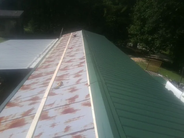 Old rusted panels beside newly installed green metal roofing — Wind Damage Roof Repair by Roofing Brothers in West Henrietta