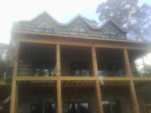 Dormers and porch framing on a large log home under construction — Roof Coating work by our crew in West Henrietta