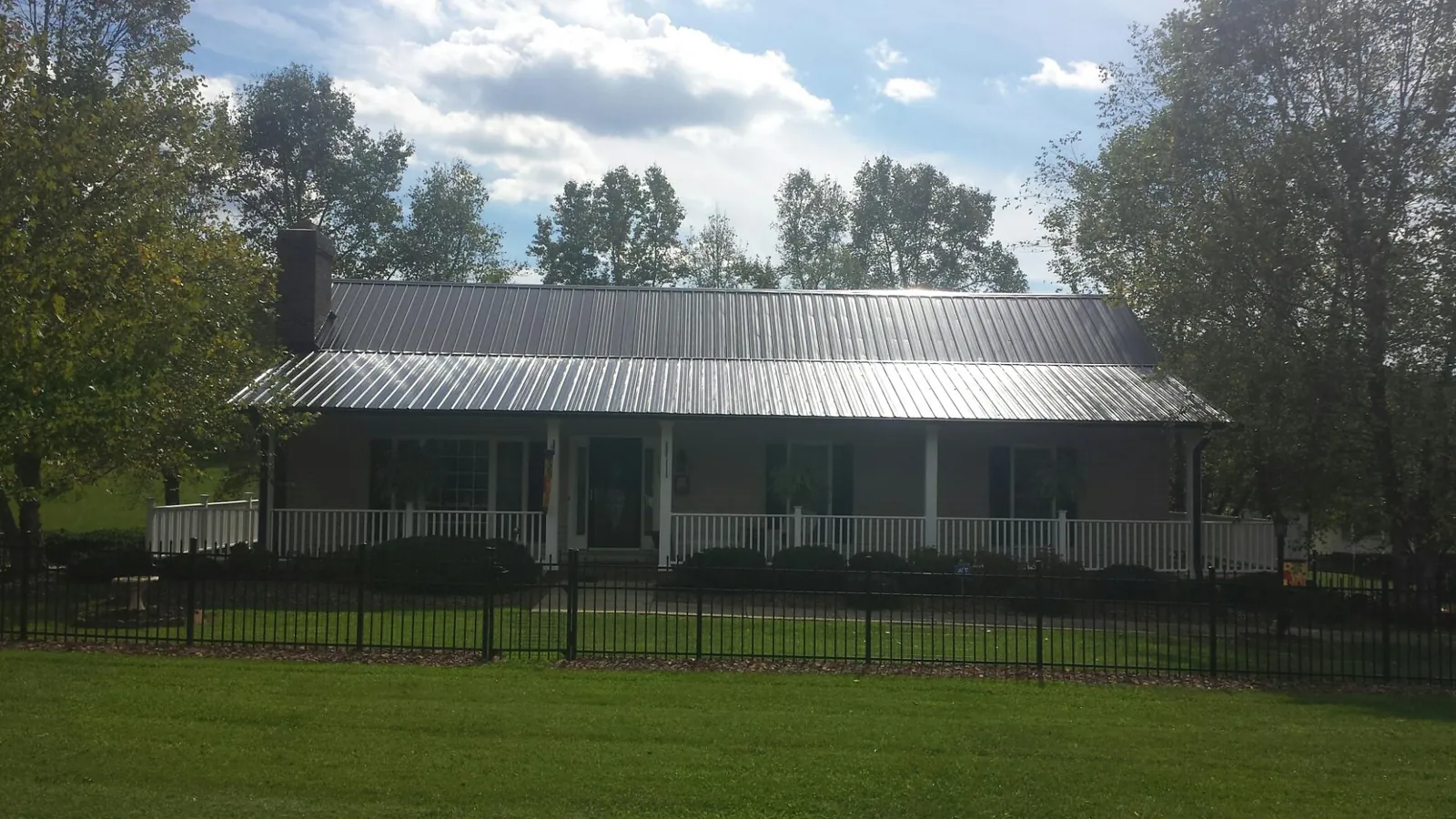 Gray metal roof on a brick ranch with a full width front porch — Gutter Guard Installation work by our crew in West Henrietta
