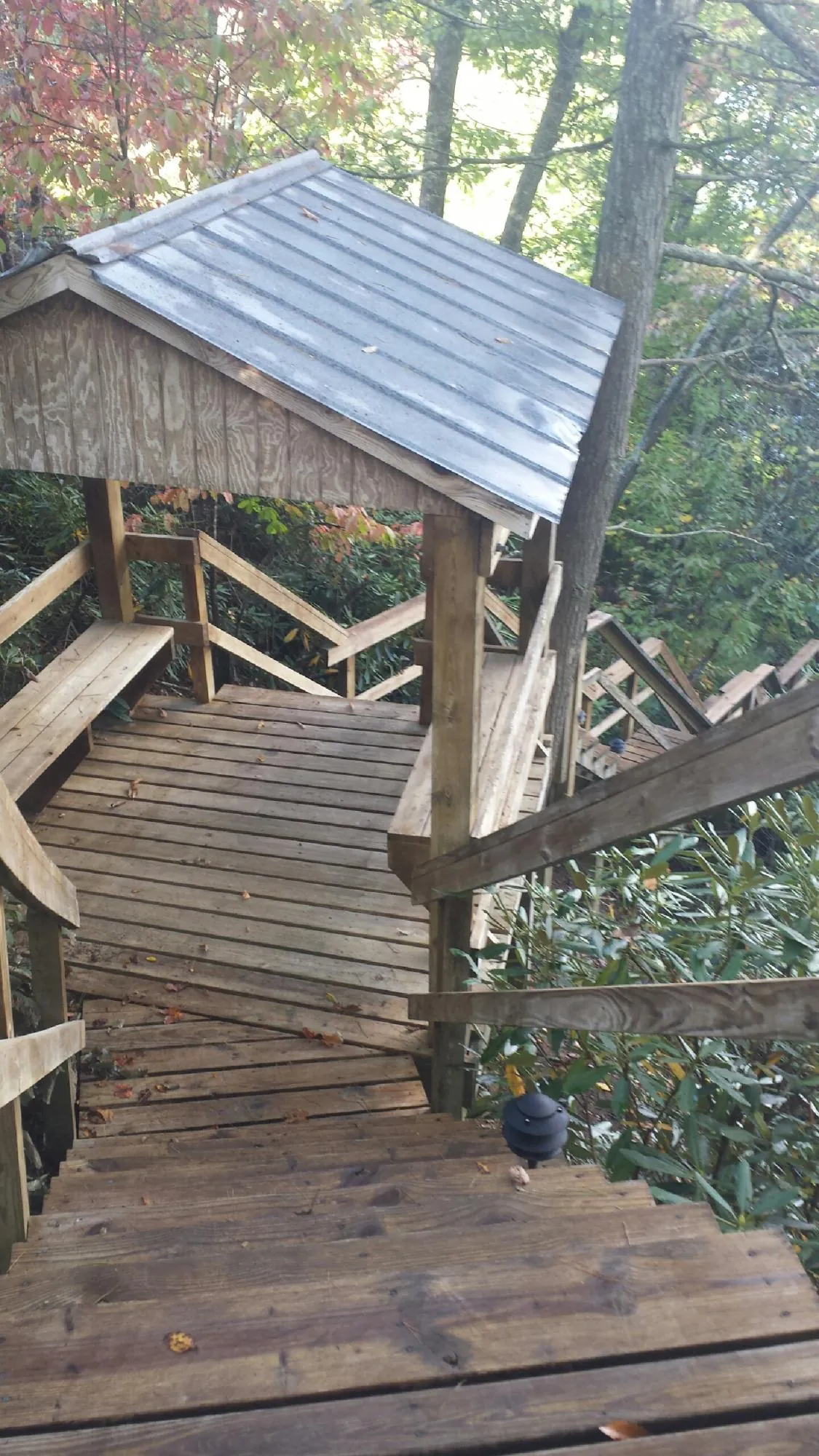 Metal roofed shelter over wooden steps on a wooded walkway — Skylight Repair & Installation work by our crew in West Henrietta