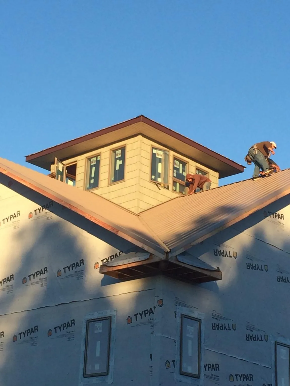 Roofers working around a rooftop cupola on a new metal roof at sunset — Roof Waterproofing in West Henrietta by Roofing Brothers